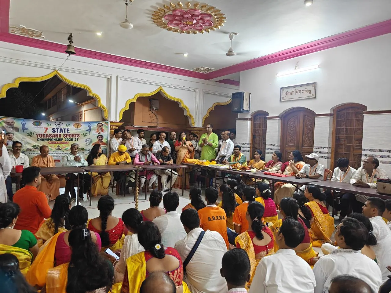 The long hall opens onto the grounds, with children seated.
