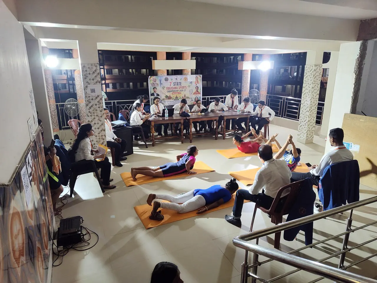 Athletes in red West Bengal kits stand on numbered mats at night.